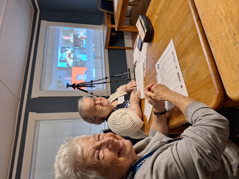 hybrid meeting 2 women in room and screen of zoom meeting