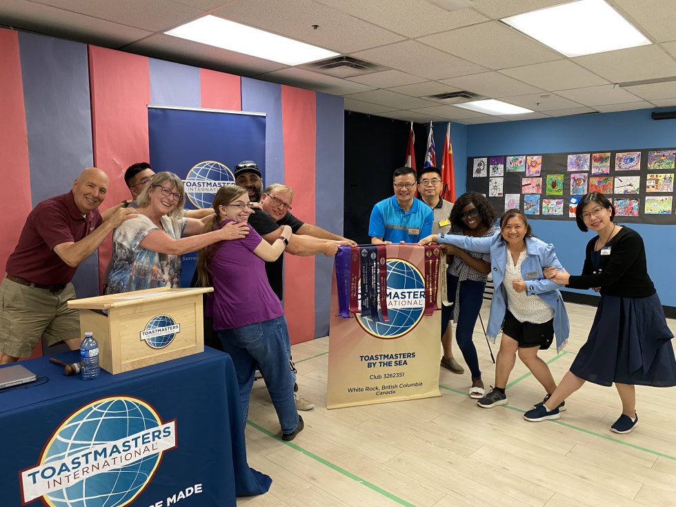 Fraser Heights Cornerstone Toastmasters club members raided Toastmasters by the Sea club’s banner in their hybrid meeting on August 20, 2023